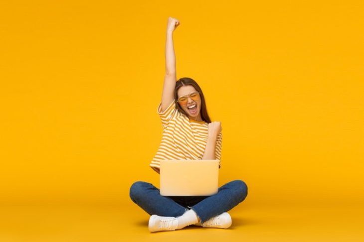 Woman cheering looking at laptop